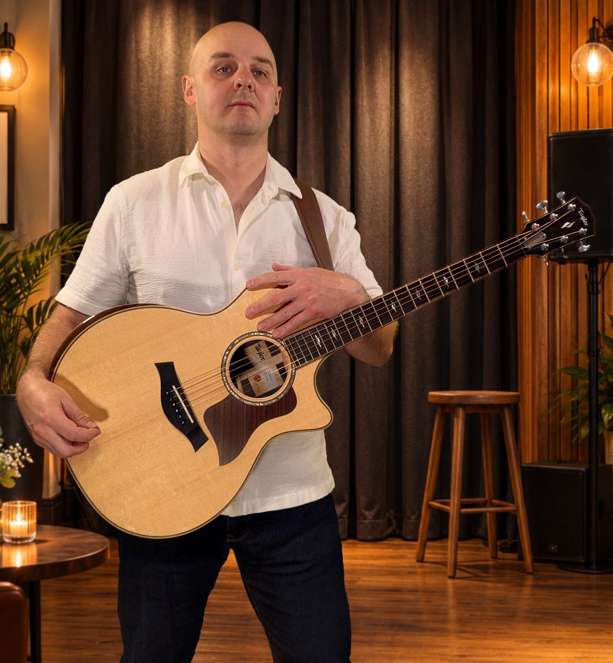 Vykintas with a Taylor acoustic guitar in a cosy event venue